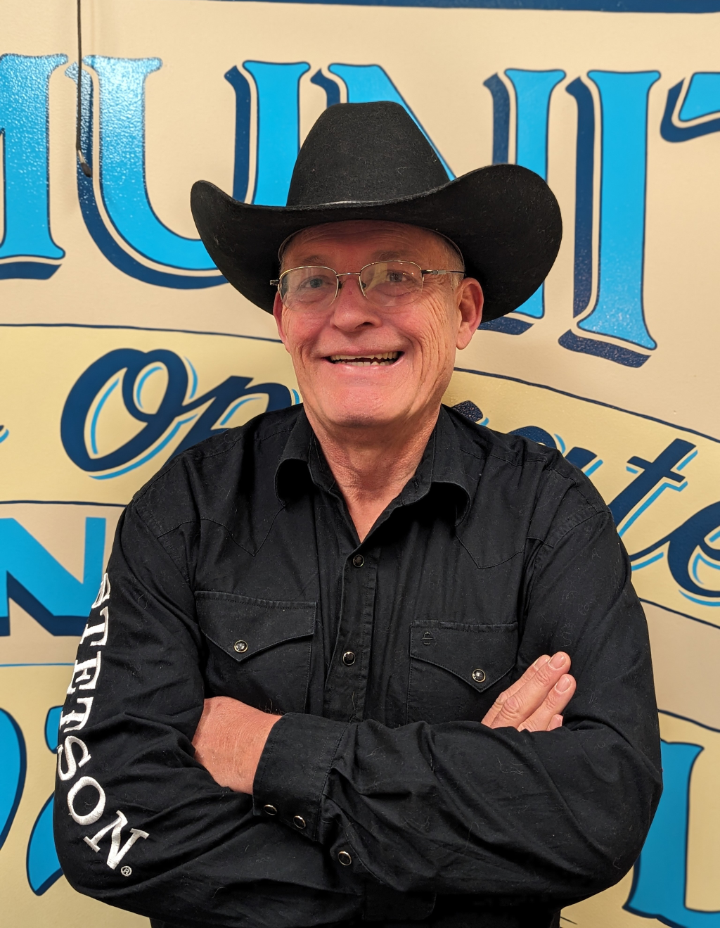 A man smiling wearing a cowboy hat
